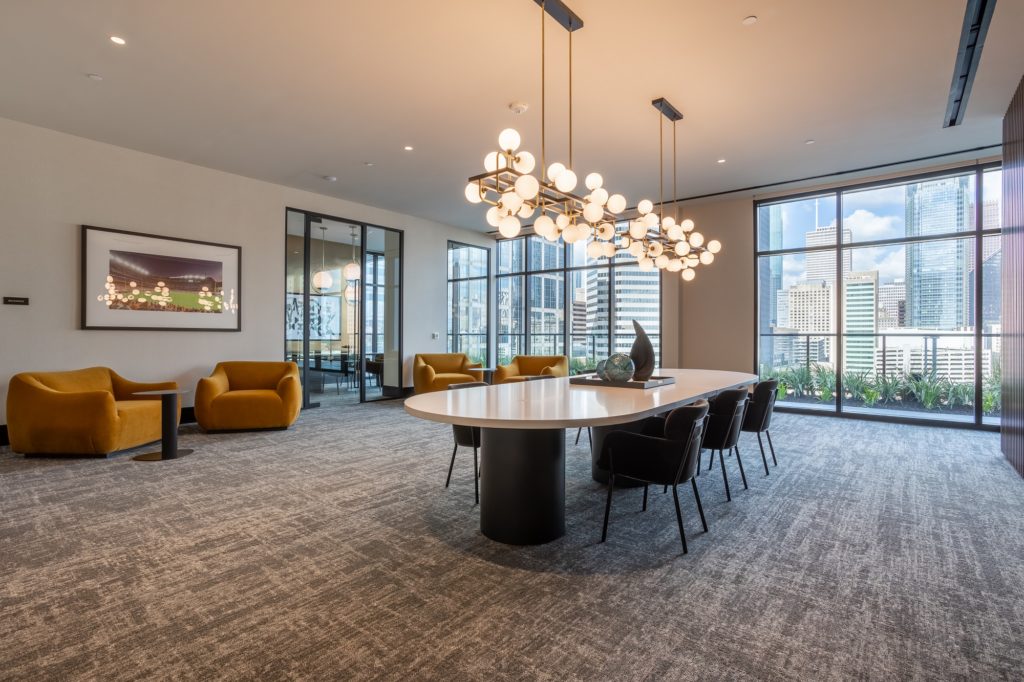 Interior shot of meeting room with designer lighting, carpet flooring, table seating, and floor to ceiling windows with downtown view