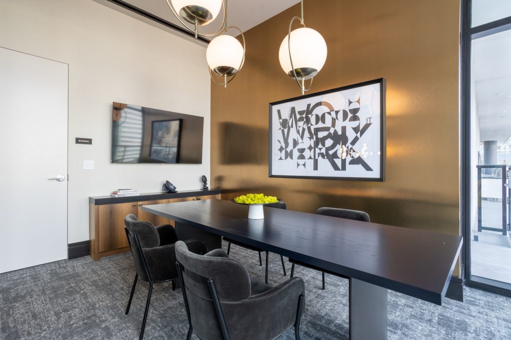 Interior shot of meeting room with table seating, carpet flooring, wall artwork, and designer lighting